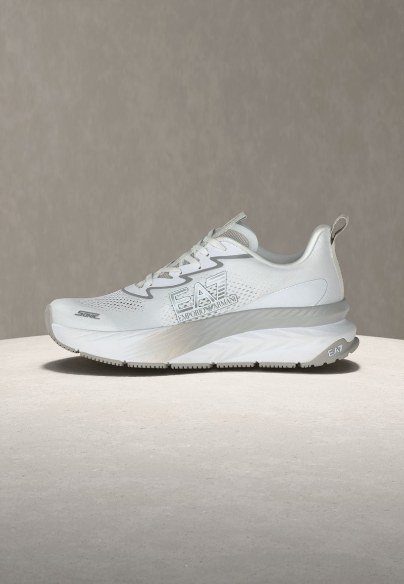 Άσπρο αθλητικό παπούτσι EA7 Emporio Armani με χοντρή σόλα, δέσιμο με κορδόνια και λογότυπο στο πλάι και τη φτέρνα σε ουδέτερο περι βάλλον.