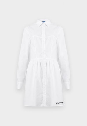 Bílé košilové šaty s dlouhými rukávy, límečkem a nápisem "Karl Lagerfeld Jeans" blízko lemu.