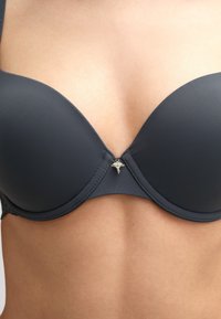 Underwire bra in dark gray satin with molded cups, featuring a decorative silver-tone charm at the center and a smooth finish.