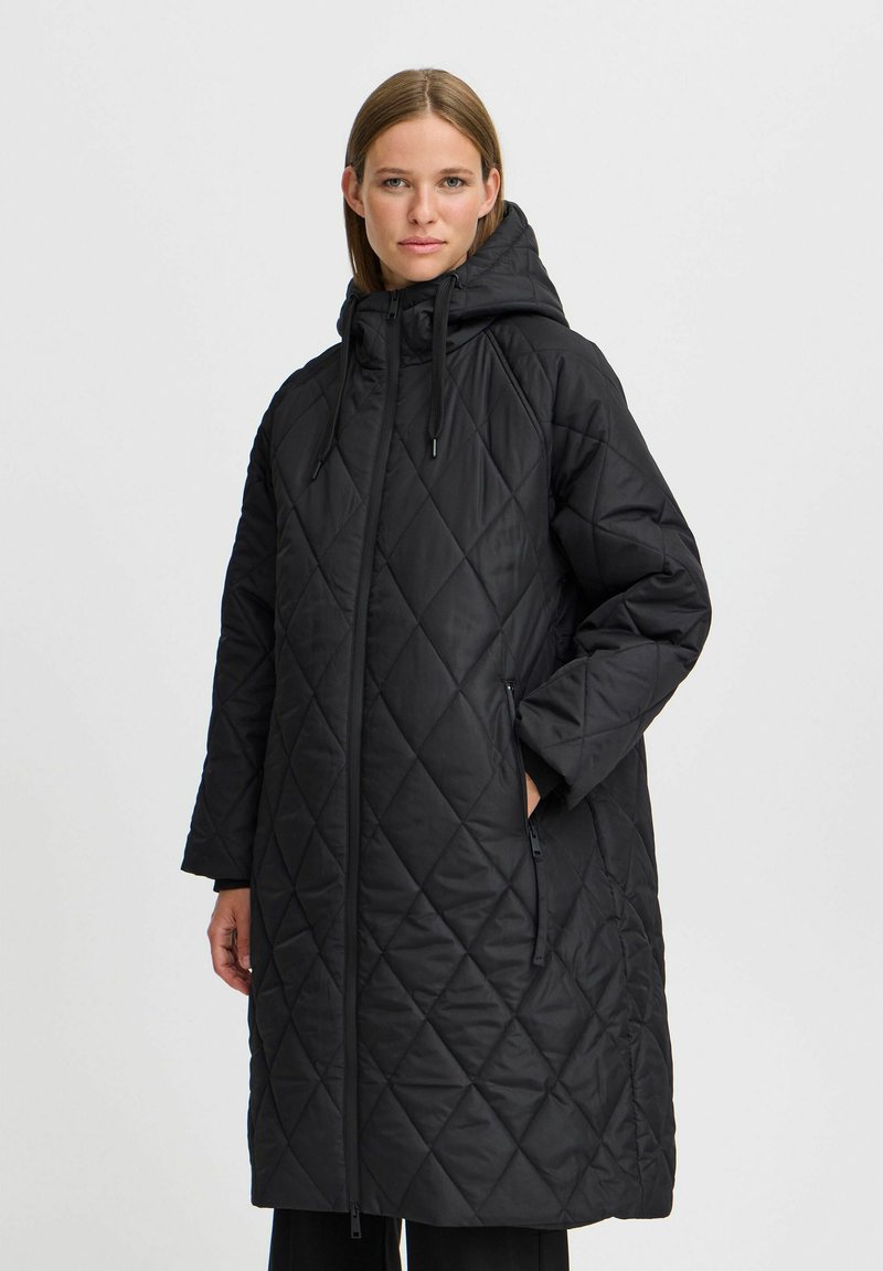 Manteau long matelassé noir avec fermeture éclair devant, capuche ajustable et poches latérales. Caractéristiques d'un motif en losanges et d'une coupe décontractée. Texture douce et mate.