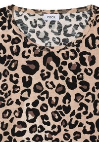 Chemise beige avec motif léopard noir et marron et col rond avec coutures visibles.