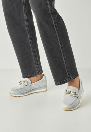 Sneakers grigio chiaro con trama intrecciata, dettaglio a catena e suola bianca. Abbinate a jeans grigio scuro a gamba dritta.