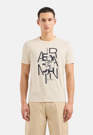 T-shirt in cotone beige con design grafico di testo in blu scuro, maniche corte e scollo a girocollo. Presenta una vestibilità comoda.