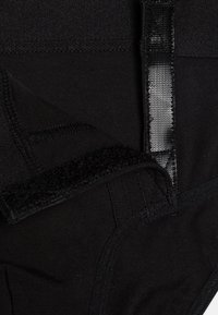 Garbore in tessuto nero con superficie testurizzata, bordi cuciti e chiusura in velcro. Il design è liscio con uno strato interno nascosto.