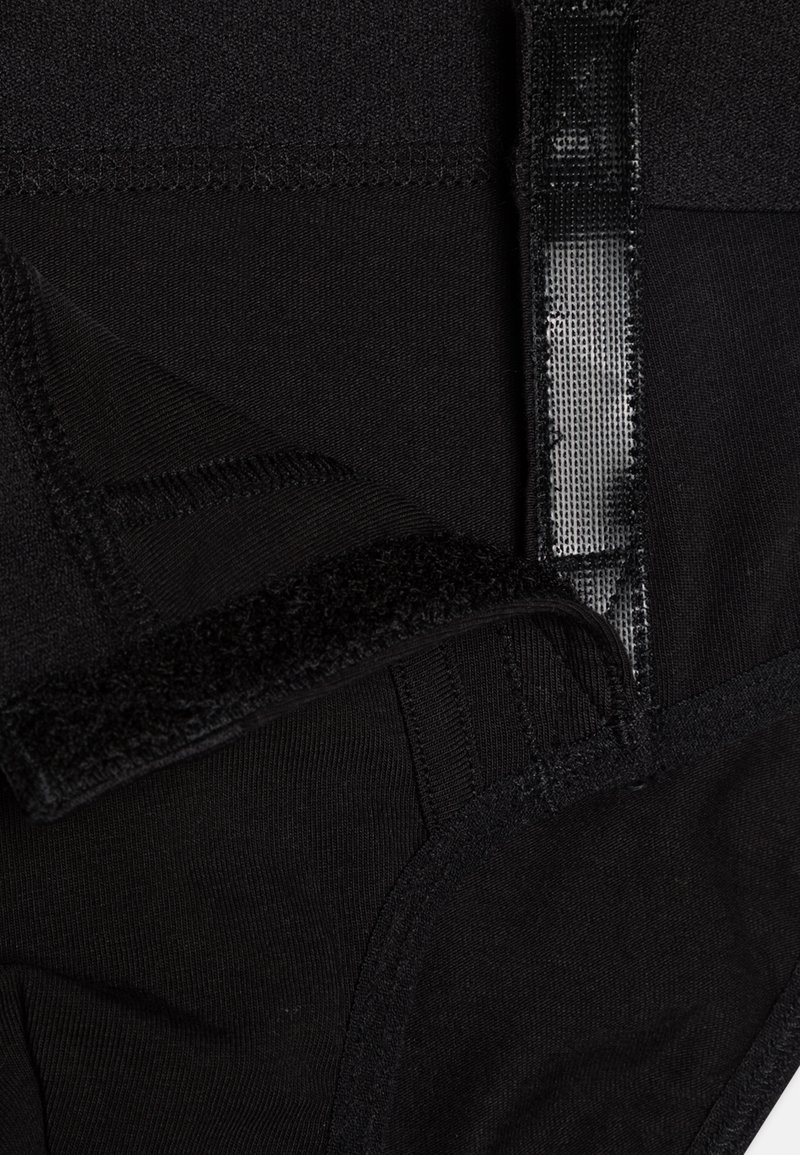 Garbore in tessuto nero con superficie testurizzata, bordi cuciti e chiusura in velcro. Il design è liscio con uno strato interno nascosto.