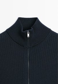 Dark ribbed turtleneck sweater with a half zipper. Features a structured neck, soft texture, and a minimalistic design in a deep navy color.