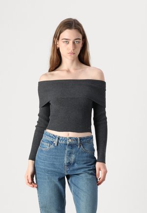 Mørk grå av-og-på skulder cropped topp med ribbet tekstur og lange ermer, paret med høy-ventet lyseblå jeans.