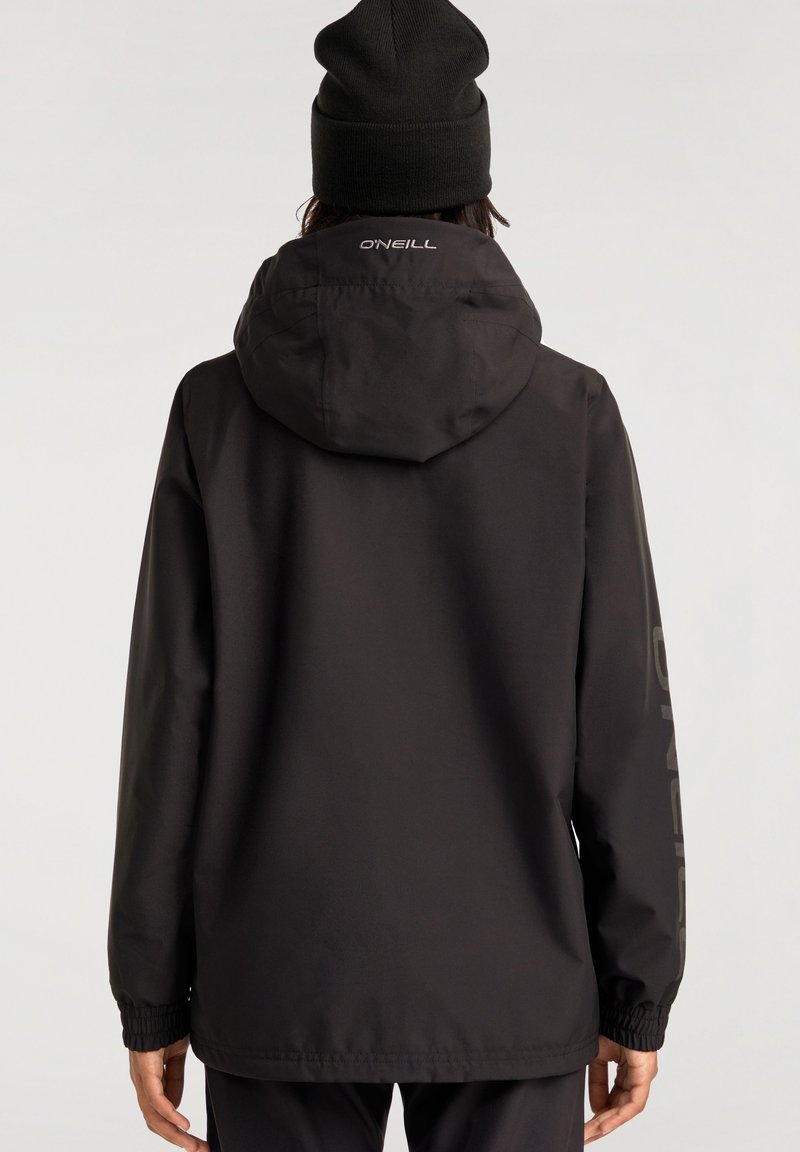 Chaqueta impermeable negra con capucha, puños elásticos y un sutil logotipo en la parte trasera. Presenta una textura lisa y mate.