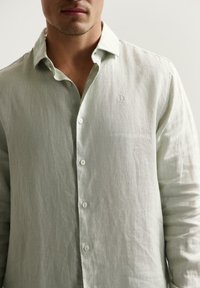 Lichte groene linnen shirt met een button-down kraag, voorzien van een klein geborduurd logo op de borst en knopen aan de voorkant.