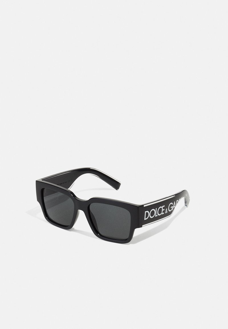 Melnas taisnstūra formas saulesbrilles ar tumšiem stikliem, ar spīdīgu apdari un "DOLCE & GABBANA" logo baltā krāsā sānos.