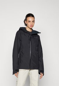 Wasserdichte schwarze Jacke mit Kapuze, mehreren Reißverschlusstaschen, anliegenden Bündchen mit Klettverschluss und einem strukturierten Innenfutter.
