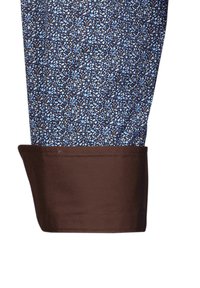 Cuff di camicia blu e marrone con un motivo floreale, caratterizzato da un tessuto strutturato e un orlo marrone uniforme.