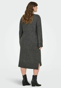 Grå stickad klänning med långa ärmar, sidöppningar och ribbade manschetter. Anmärkningsvärd dekorativ söm på ärmkanterna. Matchad med svarta ankelstövlar.