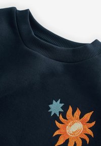 Felpa blu navy con colletto a coste, ricamata sul davanti con un sole arancione e una stella blu, tessuto strutturato e design rilassato.