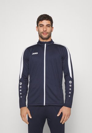 Marine sportjack met witte accenten, volledige rits, hoge kraag en logo. Bevat ronde knoopdetails op de mouwen. Gladde stofstructuur.