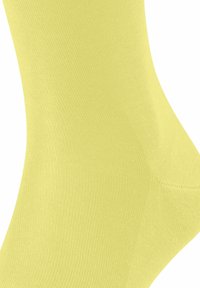 Calzino giallo alla caviglia realizzato in tessuto a coste, con una superficie liscia e una forma aderente, progettato per il comfort e l'uso quotidiano.