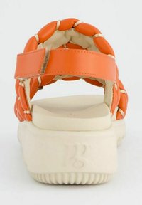 Pomarańczowe plecione sandały z wyściełanym paskiem na plecach i białą platformą. Podeszwa ma teksturowane rowki dla lepszej przyczepności.