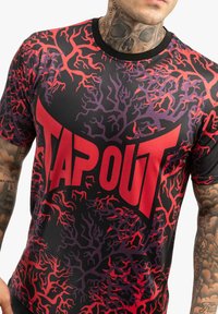 Sort kortærmet t-shirt med et rød- og lilla forgrenet mønster og "TAPOUT" i fed rød tekst over brystet. Lavet af syntetisk materiale.