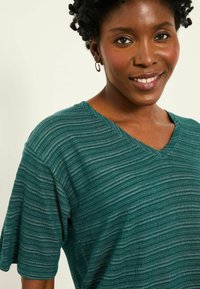 Teal short-sleeved V-neck top with horizontal stripes, featuring a soft texture and subtle sheen. Design emphasizes comfort and casual style.