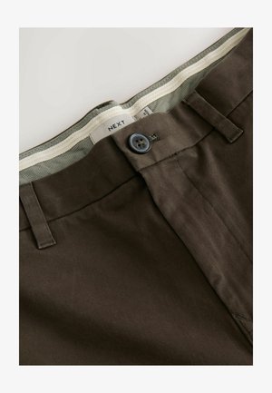 Brūni auduma bikses ar gludu tekstūru, ar pogu aizdari un rakstainu jostu iekšpusi zaļajos toņos.