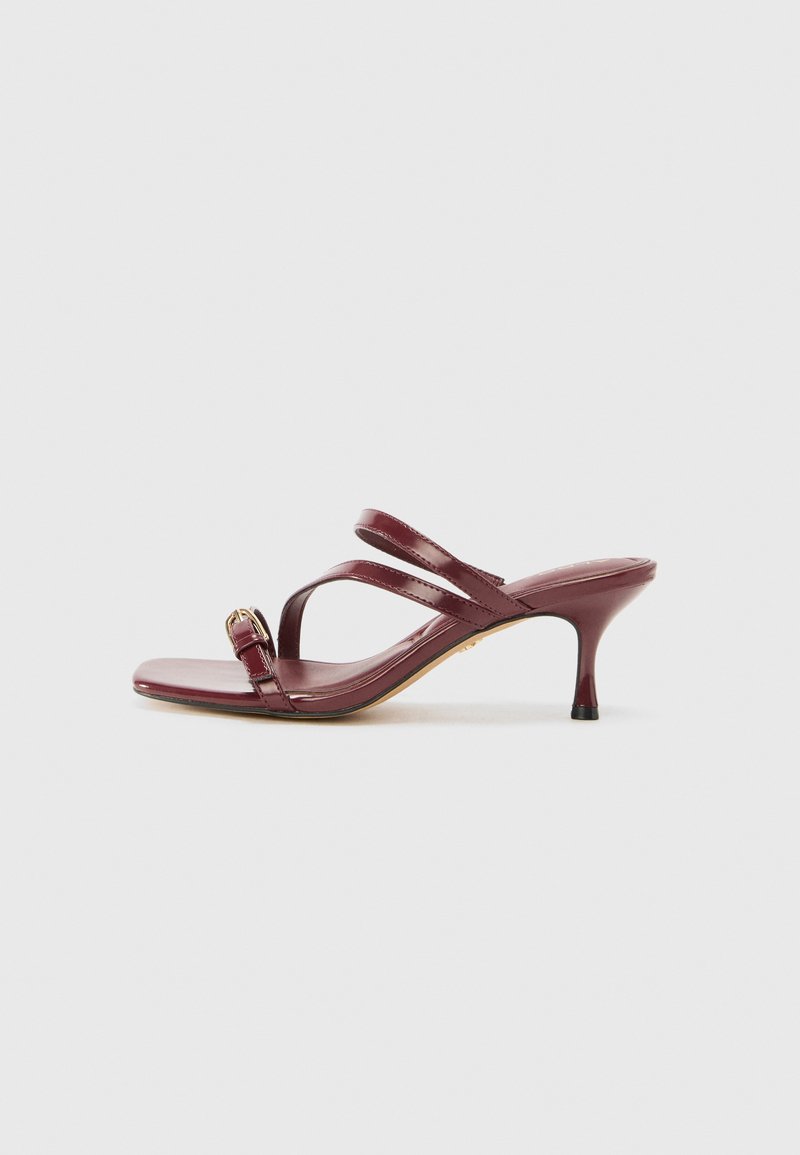 Burgundy lackläder högklackade sandaler med fyrkantig tå, två smala remmar och en dekorativ guldspänne på sidan.