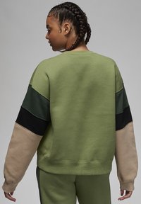 Felpa verde con design a blocchi di colore, che presenta sezioni in verde scuro, nero e beige. Texture morbida, scollatura a girocollo e polsini a costine.