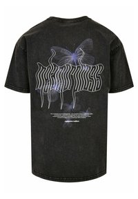 Sorte oversized t-shirt med et sommerfugl grafik og fed hvid tekst på ryggen. Stoffet har en blød, let tekstureret overflade.