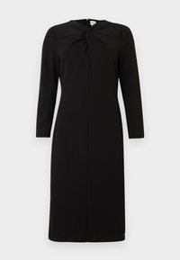 Crna midi haljina s dugim rukavima, okruglim izrezom i prednjim uvrnutim čvorom, prikazana na bijeloj pozadini.