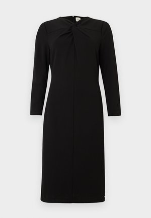 Svart midi-kjole med lange ermer, rund halslinning og frontvridd knutedetalj, vist på en hvit bakgrunn.