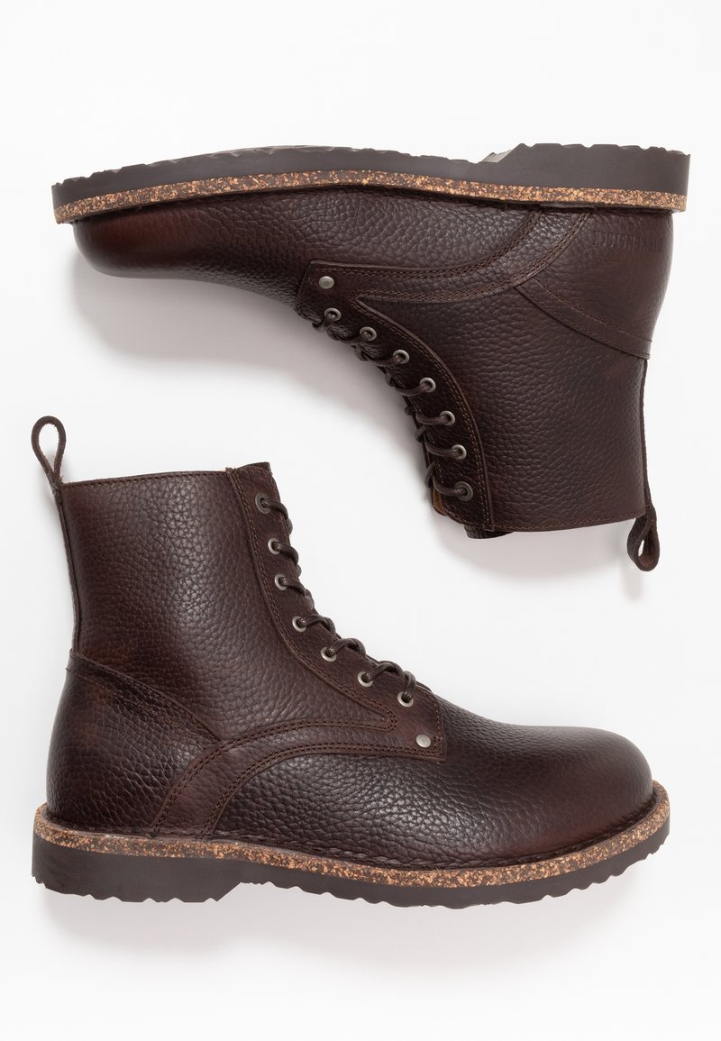 Ein Paar dunkelbraune, strukturierten Leder-Schnürstiefel mit robusten Gummisohlen und Zuglaschen, gezeigt aus Seiten- und Sohlensicht.