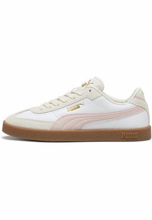 Zapatilla Puma blanca y beige con franja rosa, suela de goma, detalles dorados del logo y diseño con cordones, mostrada de lado.