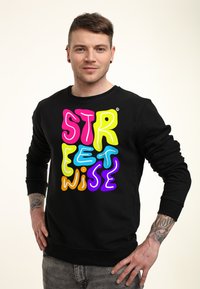 Černá mikina s dlouhými rukávy a kulatým výstřihem, zdobená multicolor stylizovaným textem "STREETWISE" v růžové, žluté, modré, oranžové a fialové barvě.
