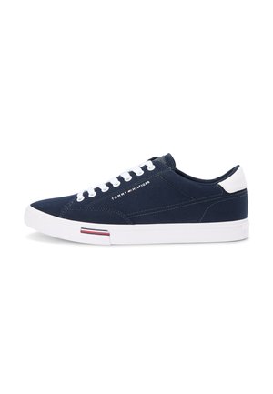 Marineblå lavtop-sneakers med hvid sål og snørebånd, "Tommy Hilfiger"-logo på siden og rød-hvid-blå stribedetalje på sålen.