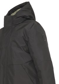 Giacca nera isolata con colletto alto, cappuccio e tessuto texturizzato. Include una toppa con logo sulla manica e una silhouette elegante.