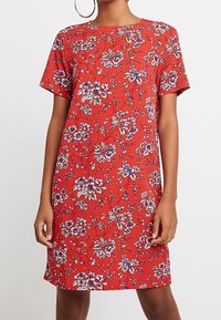 Röd kortärmad klänning med blommönster i lila och vitt, rak passform och mjuk tygkvalitet.