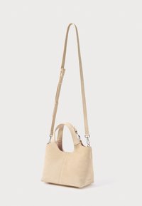 Τσάντα χειρός από μπεζ σουέντ με δομημένο σχέδιο, κοντές λαβές στο επάνω μέρος και ρυθμιζόμενο ιμάντα ώμου. Διαθέτει λεία υφή και μίνιμαλ λεπτομέρειες.