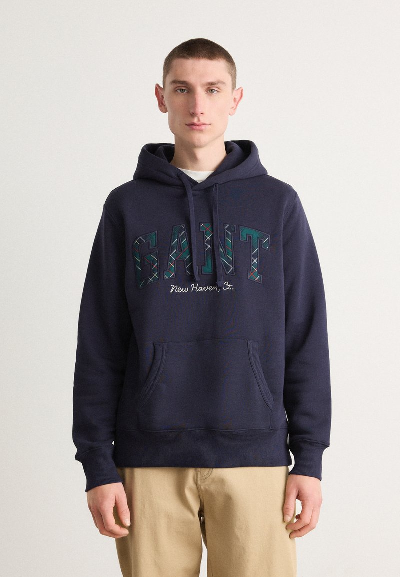 Felpa blu navy in cotone con tasca frontale, caratterizzata da un logo "GANT" multicolore e il testo "New Haven, Ct." ricamato in contrasto.