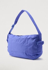 Μπλε επενδεδυμένη τσάντα ώμου με ρυθμιζόμενο λουρί και πτυχωτή λεπτομέρεια στο πλάι, τοποθετημένη σε απλό φωτεινό φόντο.