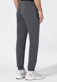 Graue tapered Sweatpants mit elastischem Bund und Bündchen, ausgestattet mit seitlichen Taschen und einem weichen Stoff. Einfaches, funktionales Design.