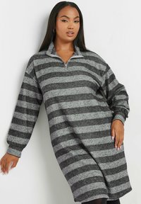 Abito oversize con zip, in strisce orizzontali alternate di nero e grigio. Tessuto a costine, maniche lunghe con polsini arricciati e colletto alto.