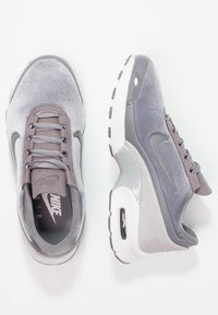 Baskets Nike Air en suède gris et mesh, avec un col rembourré, des accents de logo et un amorti air visible au niveau du talon.