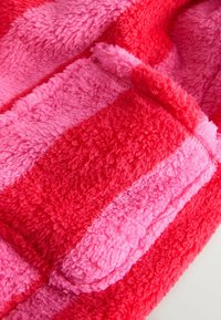 Fleece blanket featuring alternating stripes in shades of pink and red. Soft, plush texture with visible stitching along the edges.