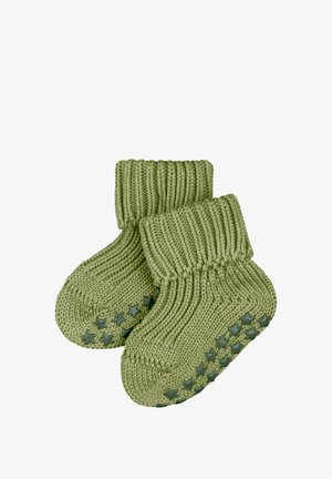 Grüne, gestrickte Babysocken mit einem gerippten Bündchen und sternmusterigem Gummi unter den Sohlen, entworfen für Komfort und Sicherheit.