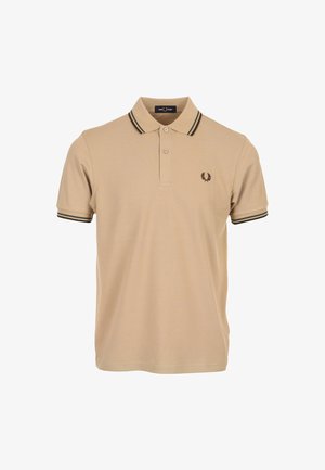 Polo beige con una placca a due bottoni, colletto e polsini a righe verde scuro e un piccolo logo sul petto sinistro. Texture liscia.