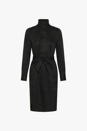 Mustast kangast pikkade varrukatega põlvpikk kleit kõrge krae ja vööga, mis on vöökohal sõlmitud, ees peidetud nööbiplaaniga.