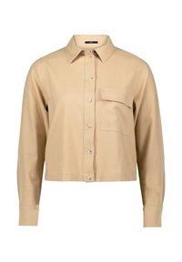 Korte beige shirt van katoen, met een klassieke kraag, knoopsluiting en een enkele borstzak. Lange mouwen met manchet.