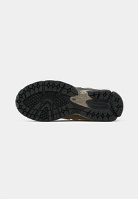 Black rubber shoe sole with a textured pattern, featuring hexagonal and linear grooves for traction, accented by light tan sections.