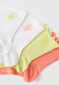 Quatre chaussettes chevilles côtelées en blanc, vert clair et corail, chacune avec des bords froncés et des initiales brodées près du bord.