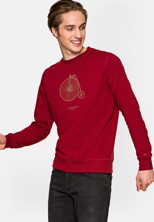 Czerwony sweter z grafiką złotego roweru z przodu, okrągły dekolt i długie rękawy, wykonany z miękkiego materiału o gładkiej teksturze.