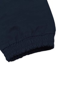 Laivansiniset housut, joissa on joustava helma, valmistettu pehmeästä kankaasta. Muotoilussa on sileä pinta ja rypytetty viimeistely hihassa.